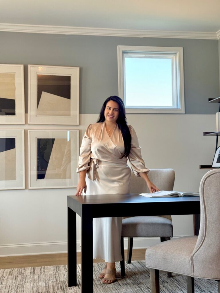Maria Alejandra Sanchez standing confidently in front of a modern office desk, representing professional leadership in Metro Atlanta real estate.